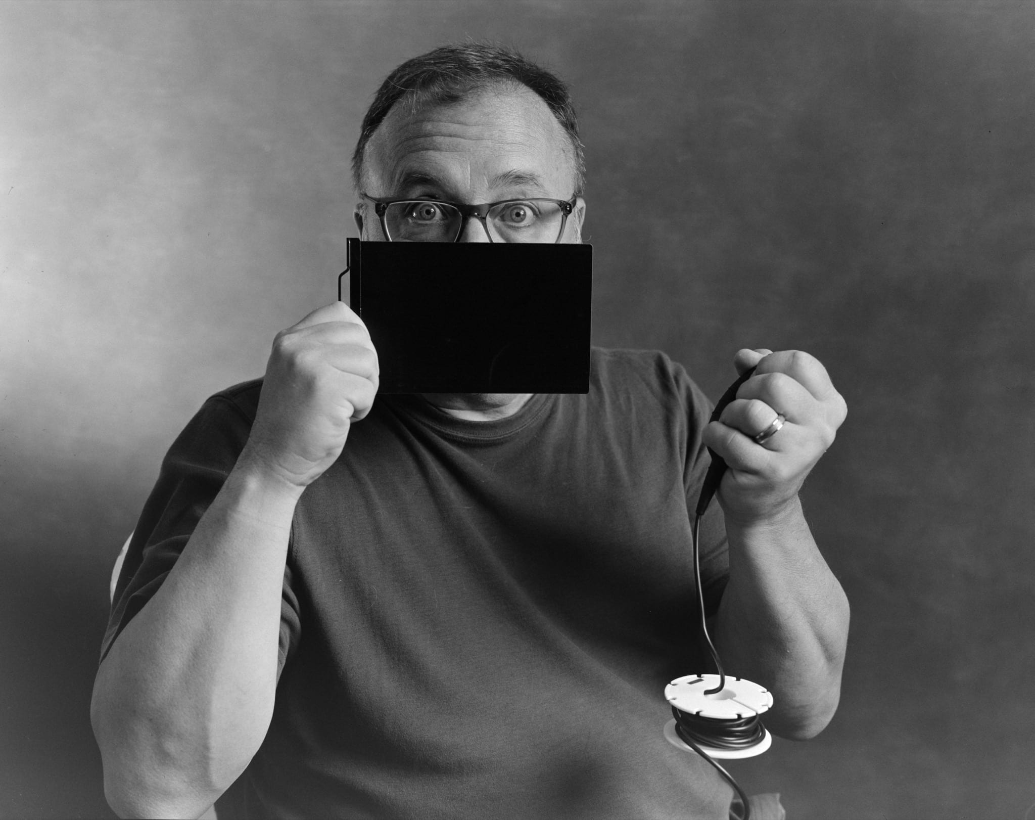 Black and white photo of man holding a 4x5 dark slide and trigger bulb