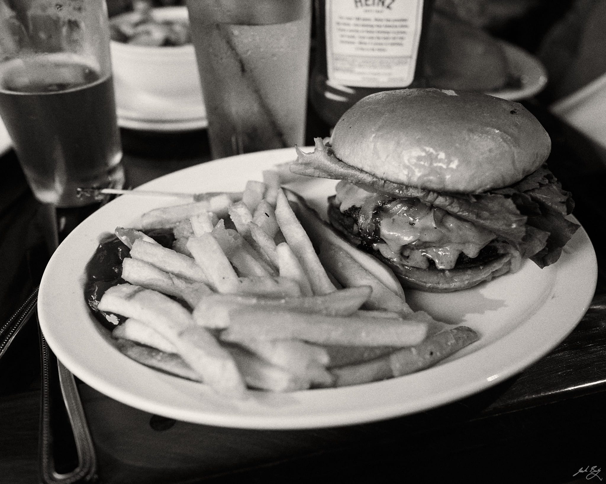 Double cheeseburger and fries on a plate in B&W